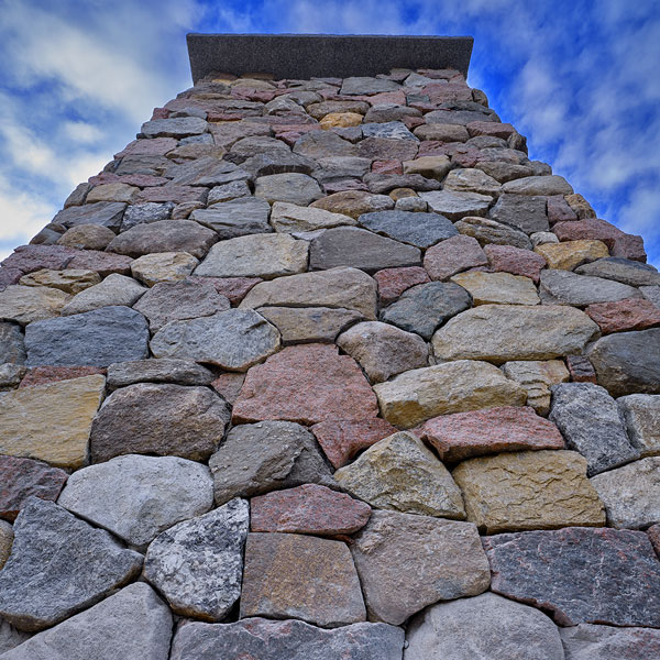 Custom made individually cut and shaped granite rock chimney with capstone by Landmark Acadia